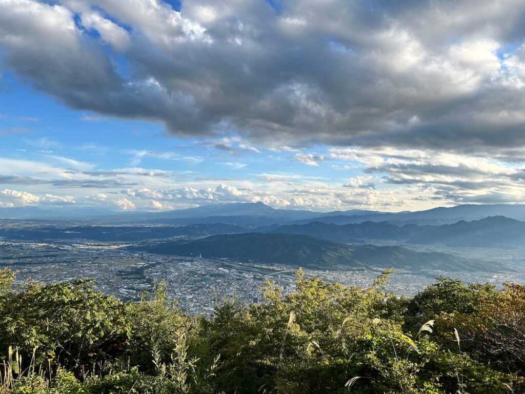 太郎山山頂から見下ろした上田市の街並みと周囲の山々の風景。自然と都市が近い上田の暮らしの全体像をイメージできる写真