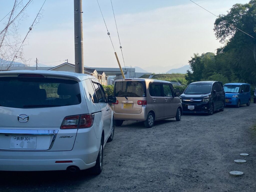 上田市の住宅地にある駐車場に複数台の車が並び、車移動が前提となる暮らしを示す写真